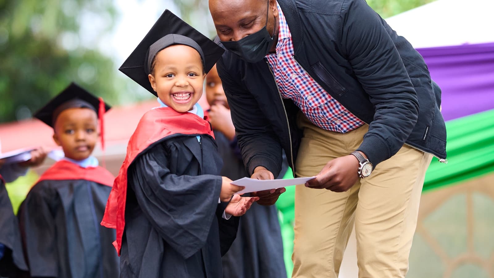 A smiling Kigwa Ridge early-years graduate receiving a certificate